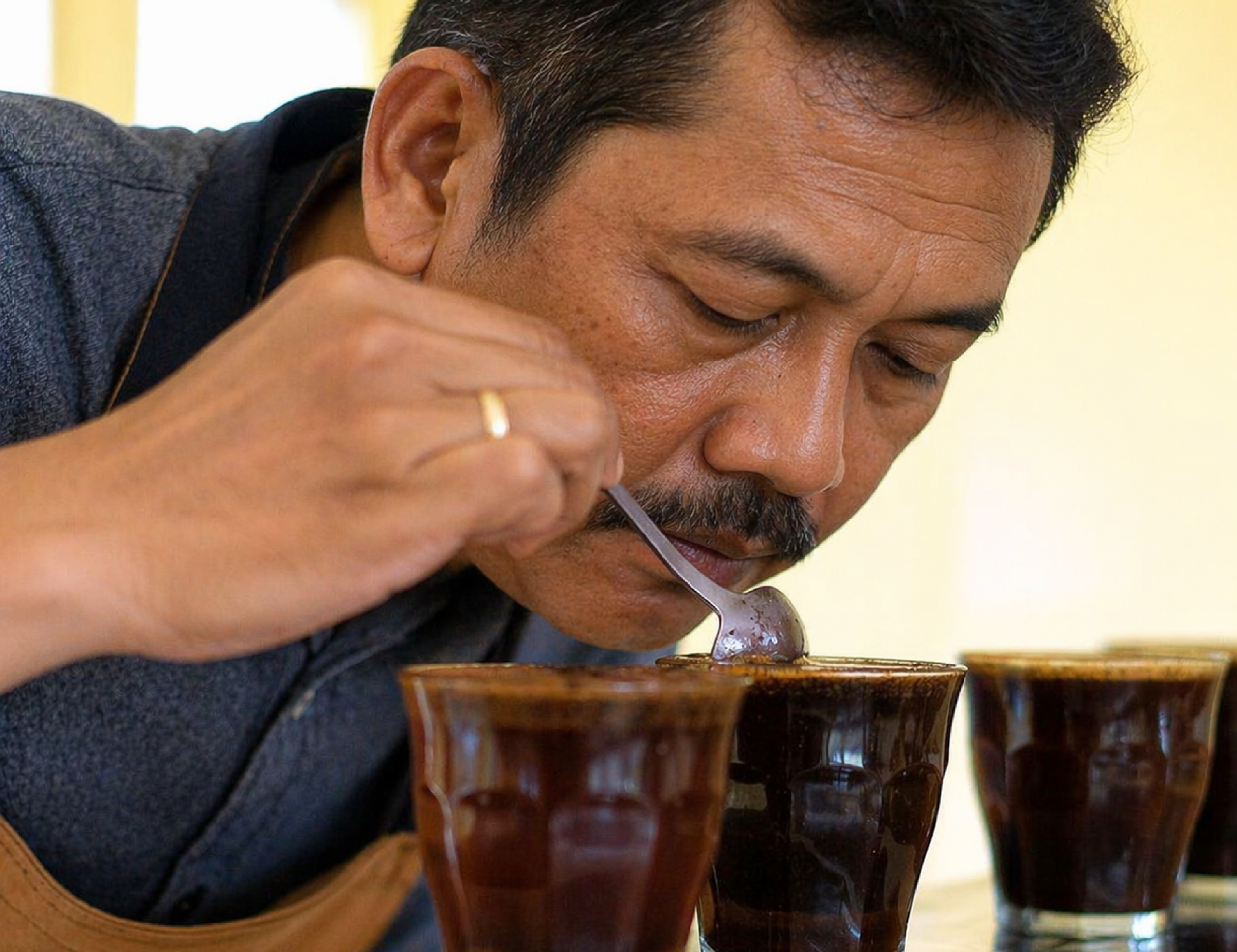 Professional coffee cupping process by Q Grader evaluating aroma and flavor using spoon technique